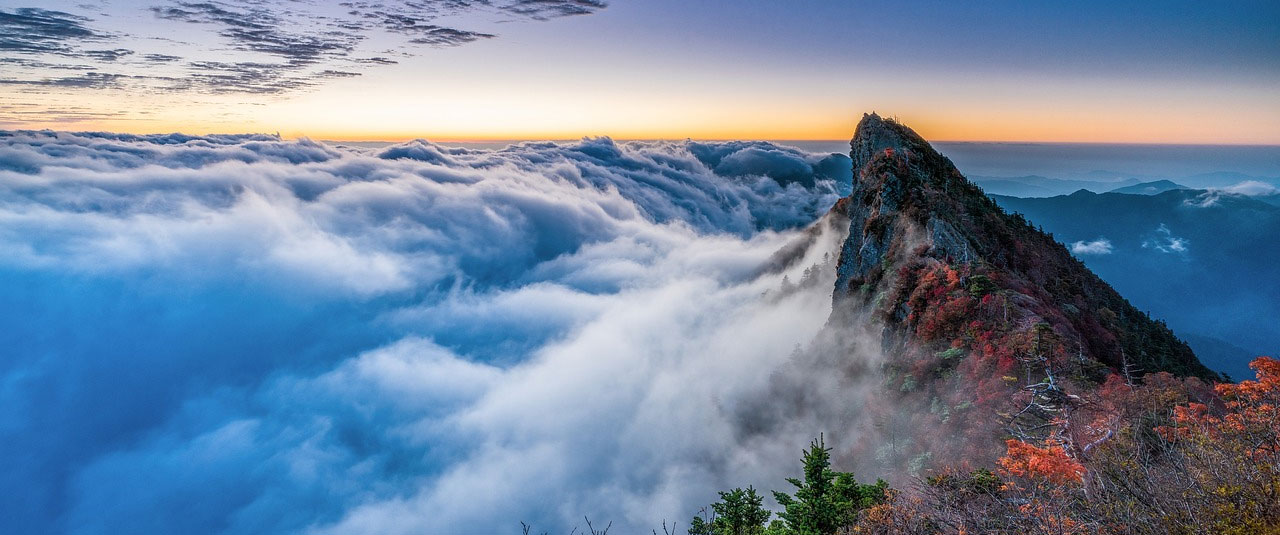 A mountain peak emerges from a layer of clouds